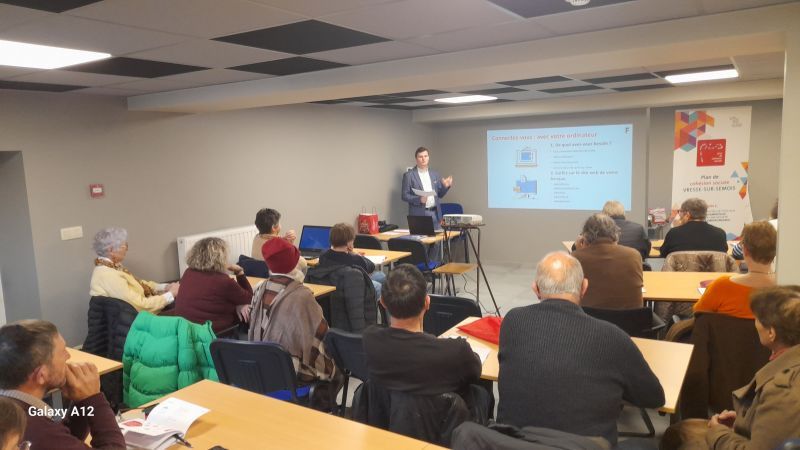 Een spreker die presenteert voor een groep aandachtig luisterende zittende mensen in een conferentiezaal.