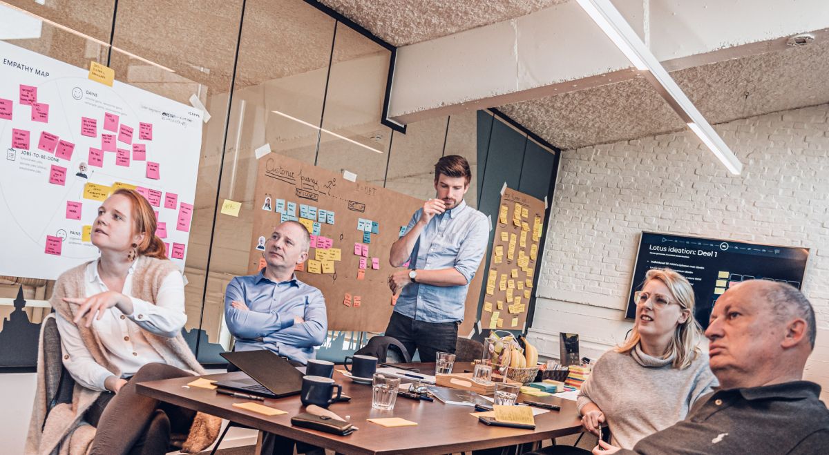 Une équipe de professionnels en réunion dans une salle de brainstorming avec des post-it colorés sur un tableau blanc